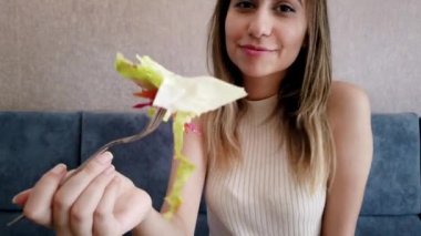 Yavaş hareket: güzel genç kız oturma sırasında bir restoran veya kafede büyük bir zevk ile salata gösterir. Gıda konsepti