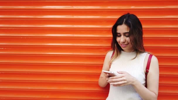 慢动作 美丽的年轻女孩采取自拍与智能手机在橙色 红色背景前 — 图库视频影像