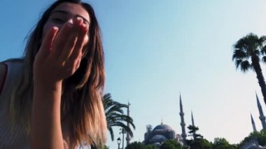 Yavaş hareket: güzel genç kız dalgaları İstanbul 'da Sultan Ahmed veya Sultanahmet Camii görünümü ile Türk bayrağı, Türkiye, seyahat konsepti