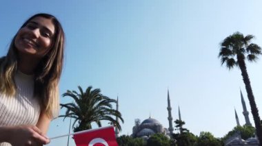 Yavaş hareket: güzel genç kız dalgaları İstanbul 'da Sultan Ahmed veya Sultanahmet Camii görünümü ile Türk bayrağı, Türkiye, seyahat konsepti