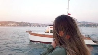 Güzel genç kız, İstanbul, Türkiye 'de boğaz ve Simgesel yapılar manzaralı bir tekne turu yaparken bir resim çeker.