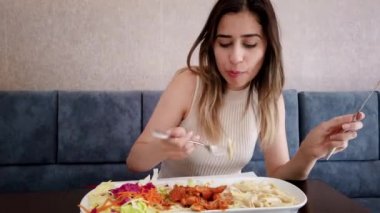 Güzel genç kız oturma sırasında bir restoran veya kafede büyük bir zevk ile tavuk yemi yiyor. Gıda konsepti