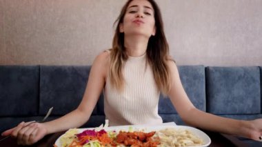 Yavaş hareket: güzel genç kız oturma sırasında bir restoran veya kafede büyük bir zevk ile tavuk yemi yiyor. Gıda konsepti