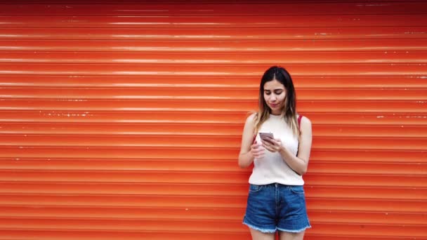 Cámara Lenta Hermosa Chica Joven Utiliza Teléfono Inteligente Delante Naranja — Vídeo de stock
