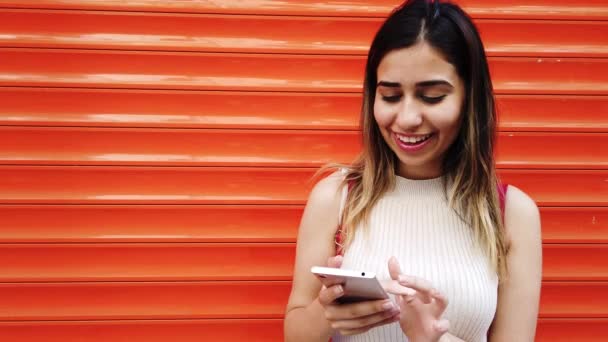 Câmera Lenta Menina Bonita Usa Smartphone Frente Laranja Fundo Vermelho — Vídeo de Stock