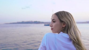 Slow Motion:Güzel kız, İstanbul'da arka planda Kız Kulesi manzarası ile Boğaz'ın gün batımı manzarasının keyfini çıkarıyor