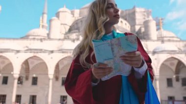 Slow Motion:Çekici güzel kız İstanbul Sultan Ahmet Camii manzaralı İstanbul haritasına bakıyor,Türkiye.Seyahat Konsepti