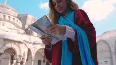 Slow Motion:Çekici güzel kız İstanbul Sultan Ahmet Camii manzaralı İstanbul haritasına bakıyor,Türkiye.Seyahat Konsepti
