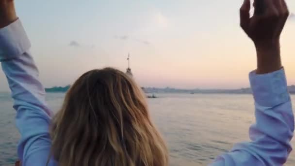 美丽的女孩享受博斯普鲁斯海峡的日落景色与在伊斯坦布尔背景的少女塔的视图 — 图库视频影像