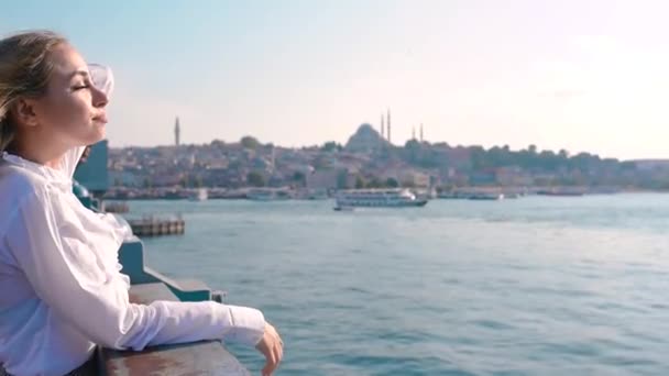 美しい女の子がガラタ橋の上に立ち イスタンブール トルコのボスポラス海峡の景色を楽しんでいます — ストック動画