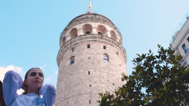 スローモーション 魅力的な若い美しい女の子は イスタンブール トルコの人気のランドマーク ガラタタワーの前でポーズ — ストック動画