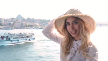 Yavaş Hareket:Güzel kız Galata Köprüsü üzerinde poz veriyor ve İstanbul'da Boğaziçi ve Süleymaniye Camii'nin manzarasına sahip.