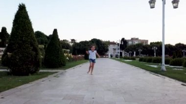 Küçük komik kızlar kameraya doğru koşar ve parkta komik şeyler yapar