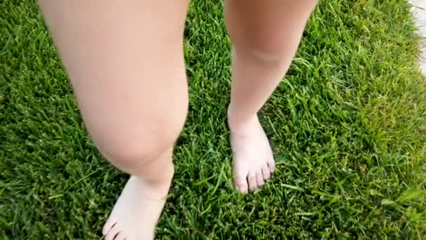 Feet of little girl while walking on grass in park or garden Stock Video. 