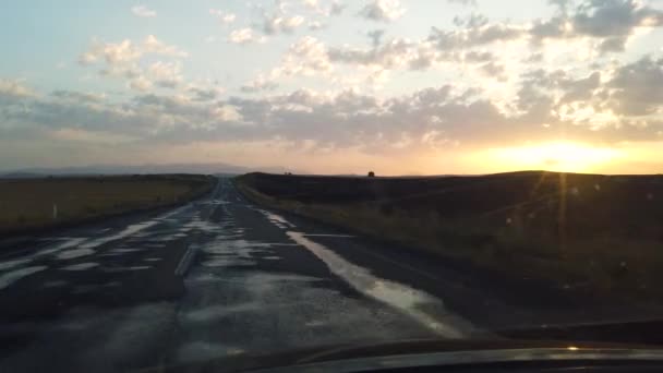 日没や日の出時に地平線に通じる空の丘陵道路の車内からの眺め — ストック動画