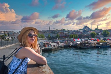 Moda giysileri içindeki güzel genç turist kız, Eminonu, İstanbul 'daki Galata köprüsündeki tarihi Süleyman Camii manzarasıyla poz veriyor. Gezgin Görüntü