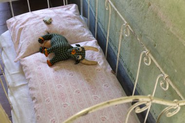 Bir üzgün ve yoksul çocukluk kavramı. Karanlık bir odada küçük bir çürük yatakta yalan yıpranmış eski el yapımı oyuncak.