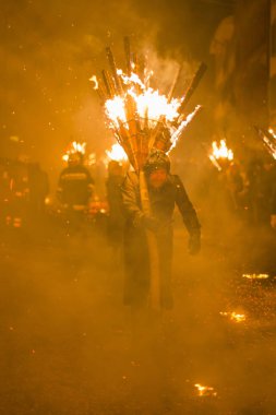 Chienbaese Festivali. İsviçre, Liestal, Rathausstrasse 25, 18 Şubat 2018. Festival katılımcıları yanan süpürge taşıyan eski kasabanın içinden omuzlarında ahşap günlükleri şeklinde.