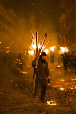 Chienbaese Festivali. İsviçre, Liestal, Rathausstrasse 25, 18 Şubat 2018. Festival katılımcıları yanan süpürge taşıyan eski kasabanın içinden omuzlarında ahşap günlükleri şeklinde.
