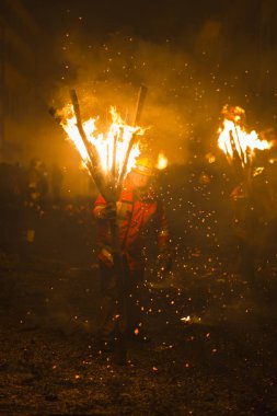 Chienbaese Festivali. İsviçre, Liestal, Rathausstrasse 25, 18 Şubat 2018. Festival katılımcıları yanan süpürge taşıyan eski kasabanın içinden omuzlarında ahşap günlükleri şeklinde.