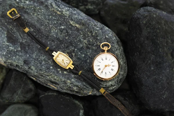 一套手表在湿绿色的石头与经典的金怀表和手表与磨损的皮革表带 — 图库照片