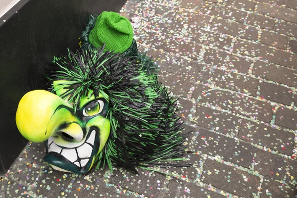 Basel karnaval 2018. Gerbergasse, Basel, İsviçre - 19 Şubat 2018. Konfeti kapsanan Caddesi üzerinde bir tek yeşil karnaval maskesi Close-up
