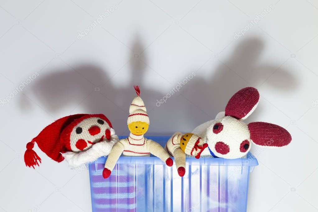 Cute and funny vintage children toys in a blue plastic box in front of a white wall. Assortment consists of a clown, a bunny and puppets.