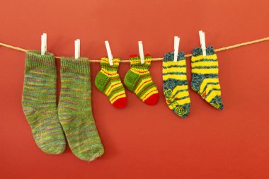 Kırmızı arka planda bir ip üzerinde renkli yünlü çorap