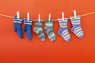 Kırmızı arka planda bir ip üzerinde renkli yünlü çorap