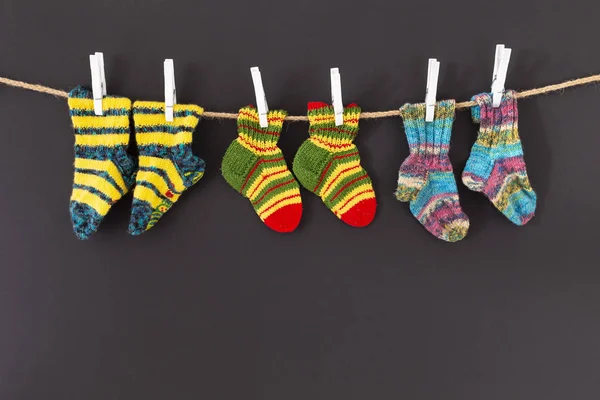 Цветные шерстяные носки на веревке на черном фоне — стоковое фото