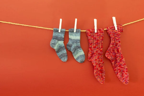 Цветные шерстяные носки на веревке на красном фоне — стоковое фото