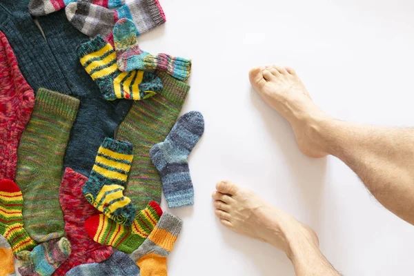 Цветные шерстяные носки и пара ног на белом фоне — стоковое фото