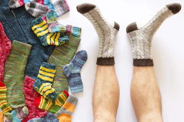 Colorful woolen socks and a pair of legs on white background
