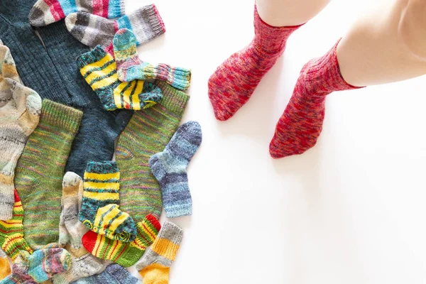 Kleurrijke wollen sokken en een paar benen op witte achtergrond — Stockfoto