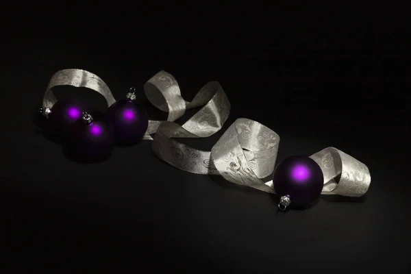 Lila Weihnachtskugeln und weiße Schleife auf schwarzem Hintergrund — Stockfoto