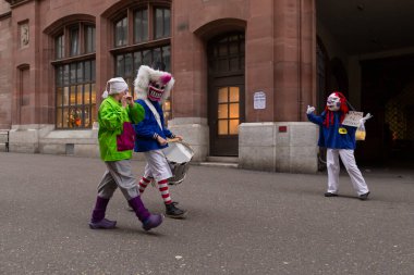 İsviçre, Basel, 3 Mart 2020. Corona virüsü salgını nedeniyle karnaval iptal edildi. Küçük bir grup katılımcı, boş sokaklardan geçerek sosyal mesafeyi taklit ediyor.