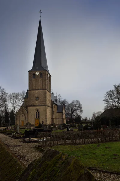 Mezarlık ve bulutsuz gökyüzü ile Kalkar Hoennepel St. Regenfledis kilisede
