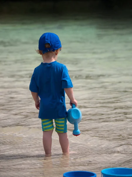 su mavi gömlek ve kap ile plajda durup küçük şirin çocuk