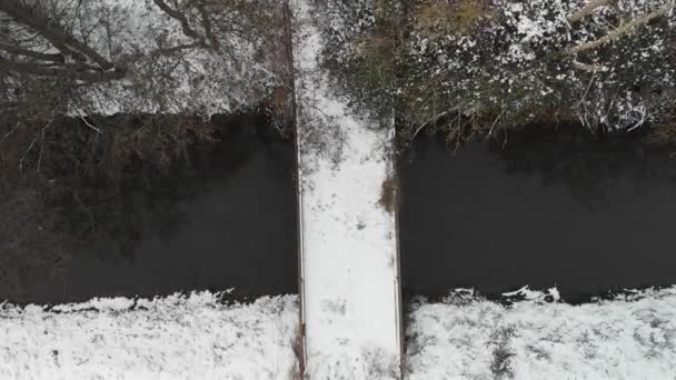 Drone Desciende Directamente Pequeño Puente Nevado Sobre Arroyo — Vídeos de Stock