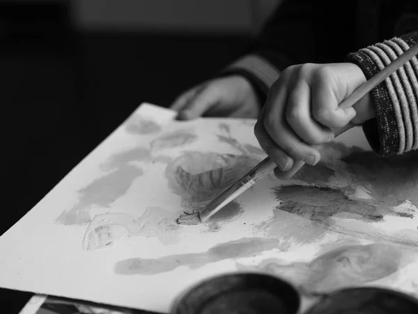 Bir çocuk bir fırça ve suluboya ile bir resim boyar, siyah beyaz resim bölüm 1