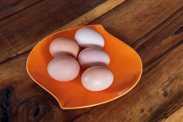 木制背景桔子盘上新鲜的褐色和白色鸡蛋 — 图库照片