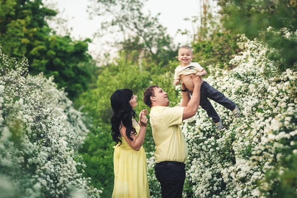 Concepto de familia feliz. Papá levanta a su pequeño hijo con las manos en alto. Los padres juegan con el niño . — Foto de Stock