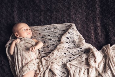 Yeni doğan bebek battaniye içinde yatıyor ve uzak görünüyor