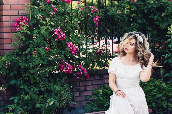 Retrato al aire libre de joven hermosa chica rizada cerca de red forjada con rosas . — Foto de Stock