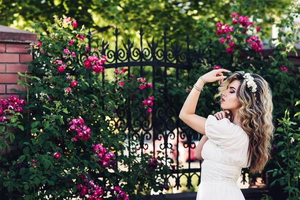 아름 다운 곱슬 소녀 장미와 단조 격자 근처의 야외 초상화. — 스톡 사진