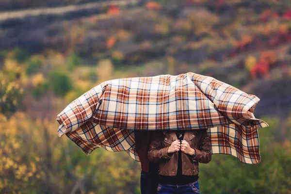 Man and woman hid their heads under brown rug in autumn — Stock Photo, Image