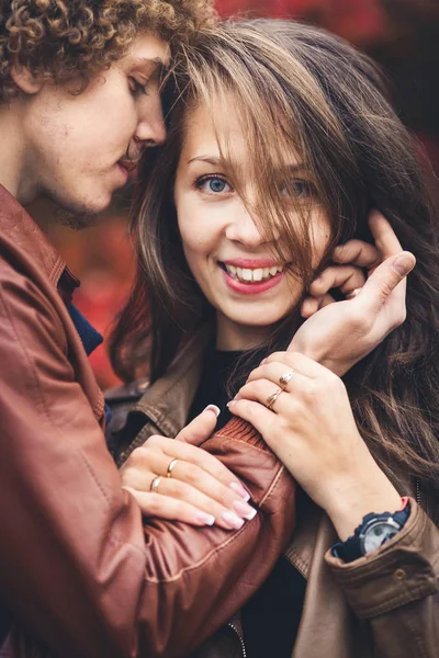 Hombre bigote de pelo rizado y mujer morena abrazándose en otoño contra el fondo de los árboles rojos . —  Fotos de Stock