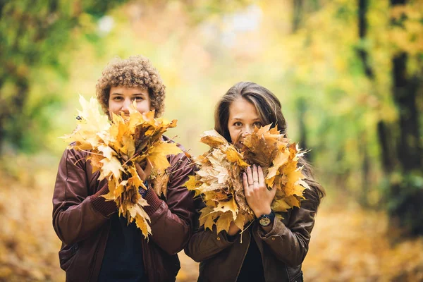 Ragazzo e ragazza tenere in mano un sacco di foglie d'acero autunno e chiudere i loro volti . — Foto Stock