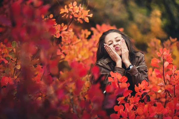 Alegre chica feliz presiona sus mejillas con las manos y muestra emociones en otoño . — Foto de Stock