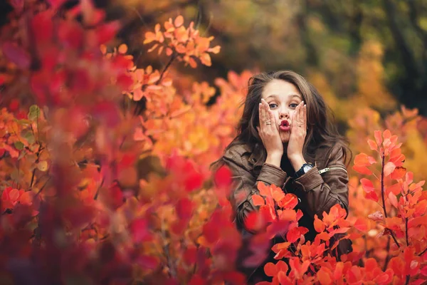 Alegre chica feliz presiona sus mejillas con las manos y muestra emociones en otoño . — Foto de Stock